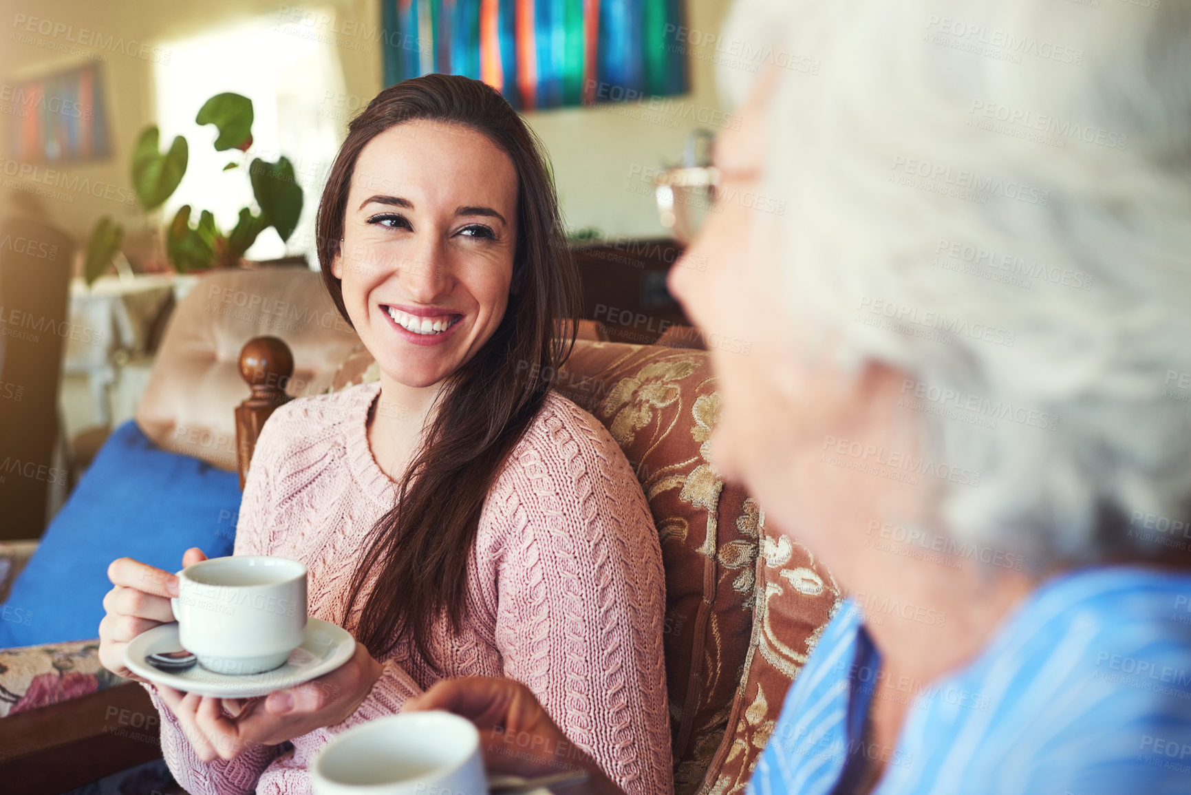 Buy stock photo Elderly mother, happy daughter and drinking coffee for bonding, reunion and conversation in home. Women, senior mom and adults with tea in living room for story, advice and family generations talking