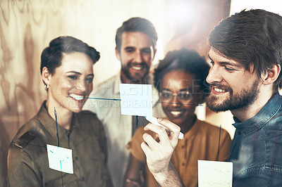 Buy stock photo Shot of a group of businesspeople brainstorming with notes on a glass wall
