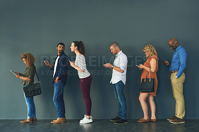 Buy stock photo Shot of a group of people standing in a row behind each other while using their phones