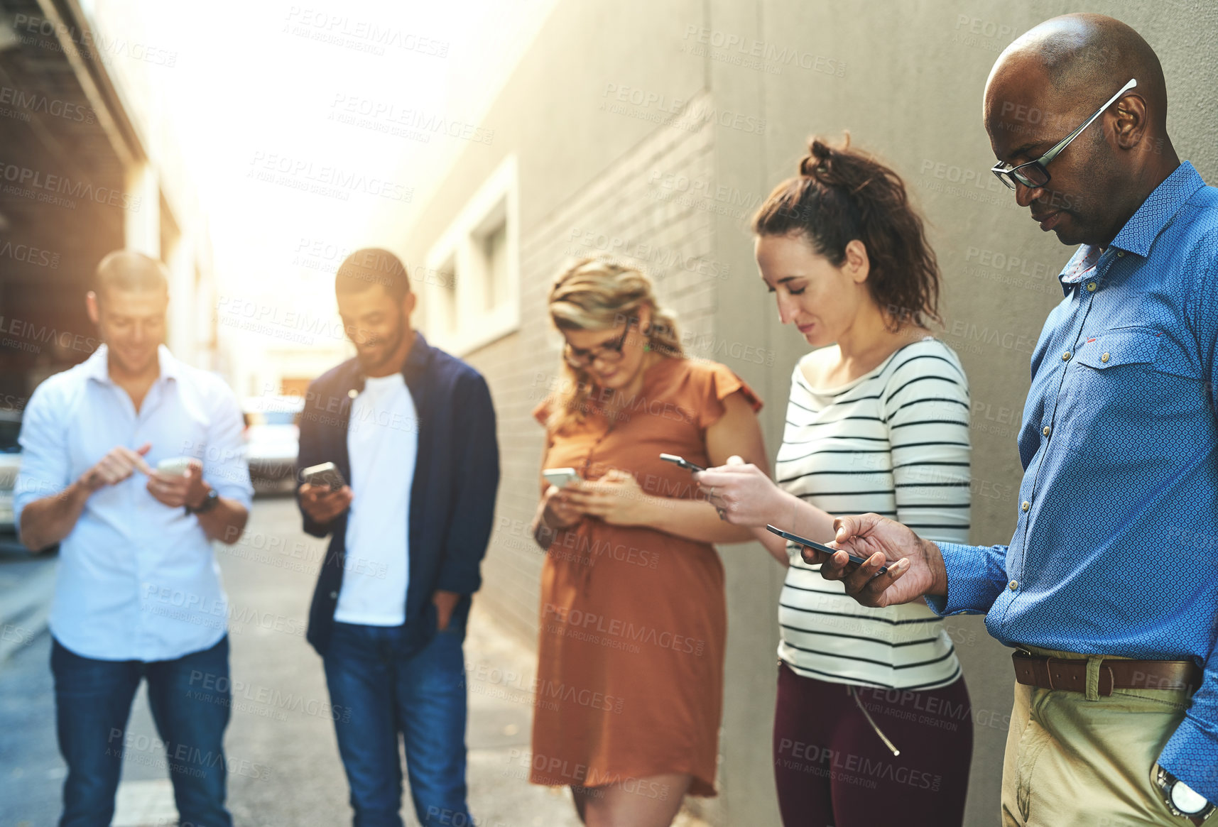 Buy stock photo Diverse group of adult people connecting and social networking outside. Businesspeople texting, browsing and sharing information on phones online while out of the office on a break from work.