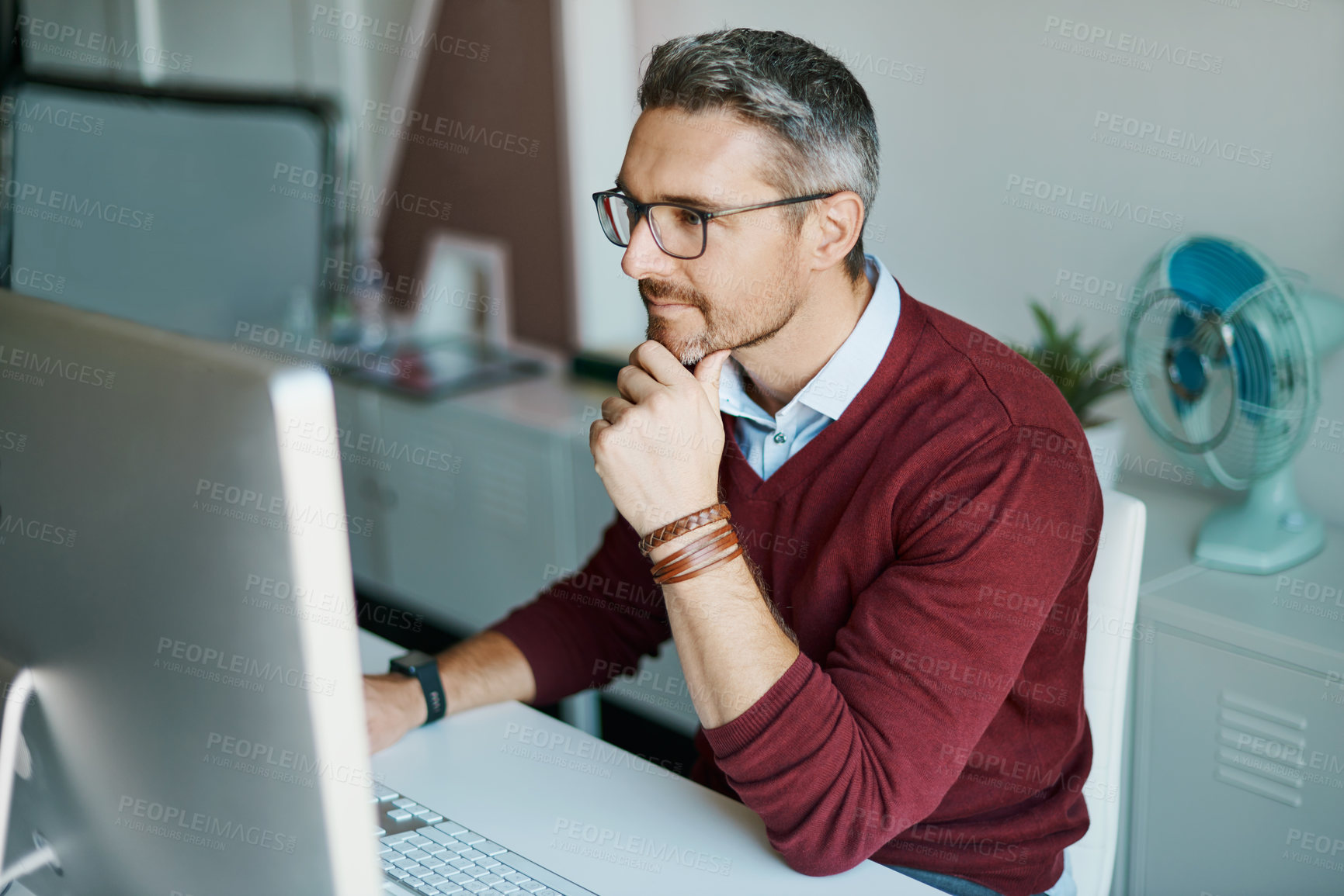 Buy stock photo Shot of a mature businessman working on a computer in an office
