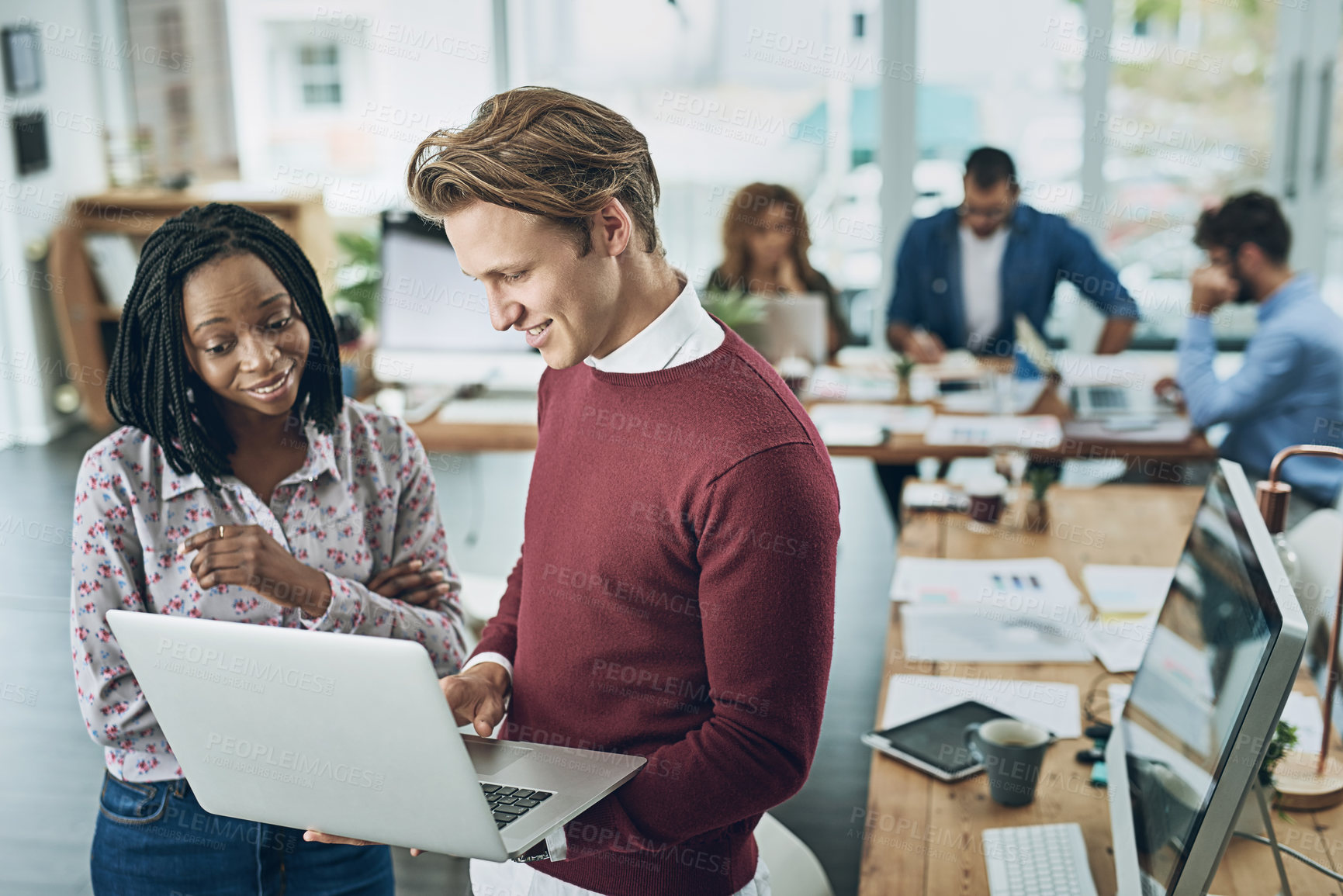 Buy stock photo Shot of two young colleagues using a laptop together in a modern office