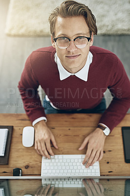 Buy stock photo High angle shot of a young man using a computer at his desk in a modern office