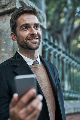 Buy stock photo Cropped shot of a handsome businessman using his cellphone while about town