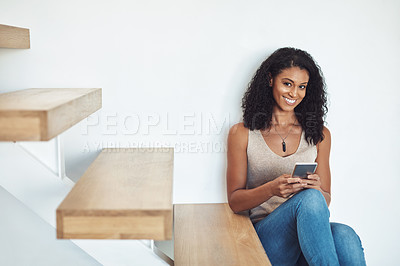 Buy stock photo Happy woman typing on phone, texting a message on social media or browsing the internet while sitting on stairs at home. Portrait of a confident, beautiful and female relaxing on wooden steps.