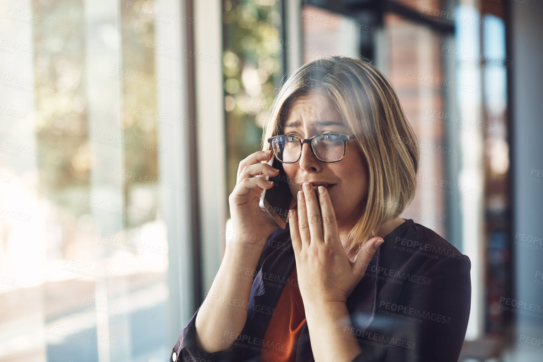 Buy stock photo Shot of a young woman looking distraught while talking on a mobile phone in a modern office