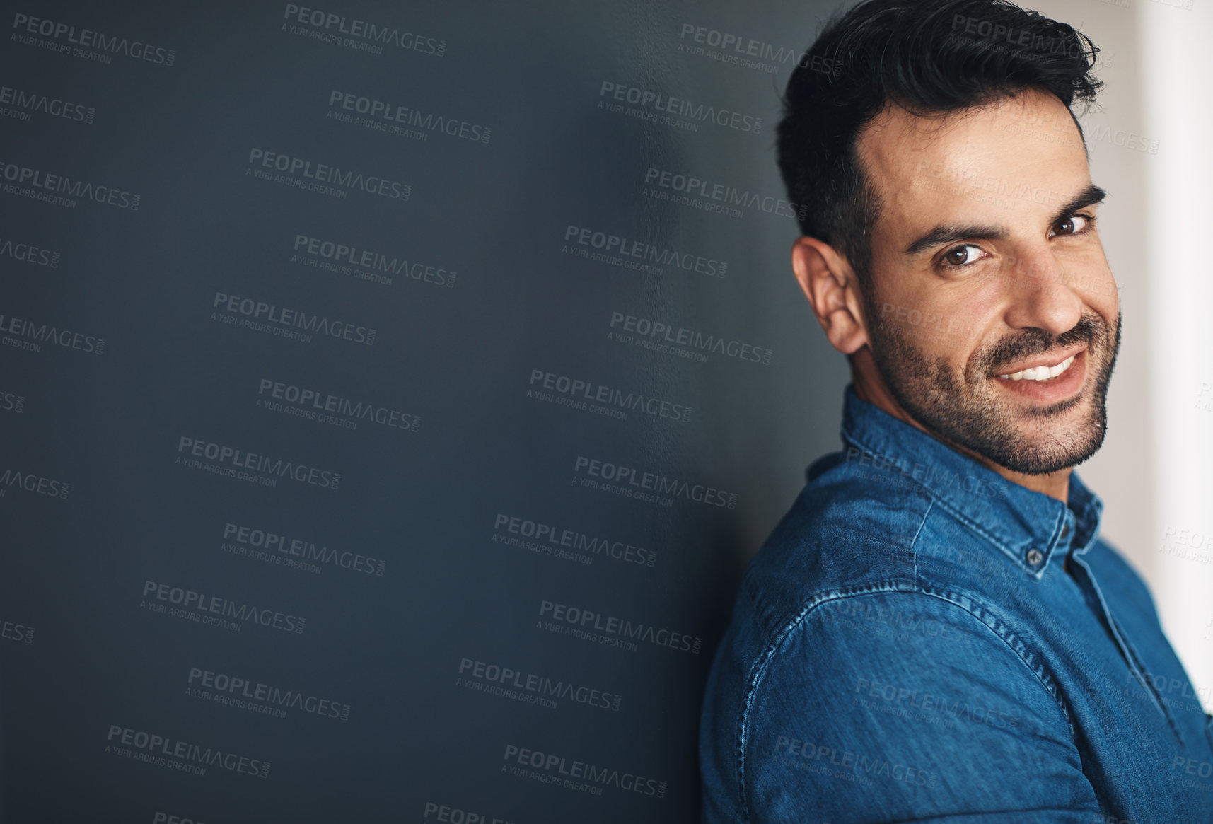 Buy stock photo Happy, confident and smiling business man or entrepreneur in an office with copy space. Ambitious and determined male employee leaning against a wall at work. Feeling positive and working for success