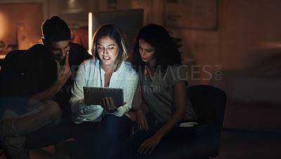 Buy stock photo Shot of a group of colleagues using a digital tablet together during a late night at work