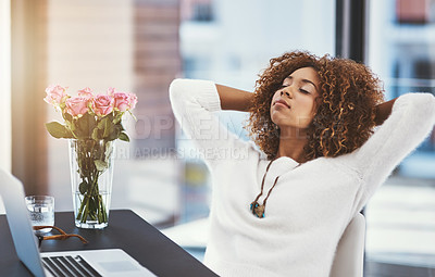 Buy stock photo Shot of a young entrepreneur leaning back in her chair with her hands behind her head