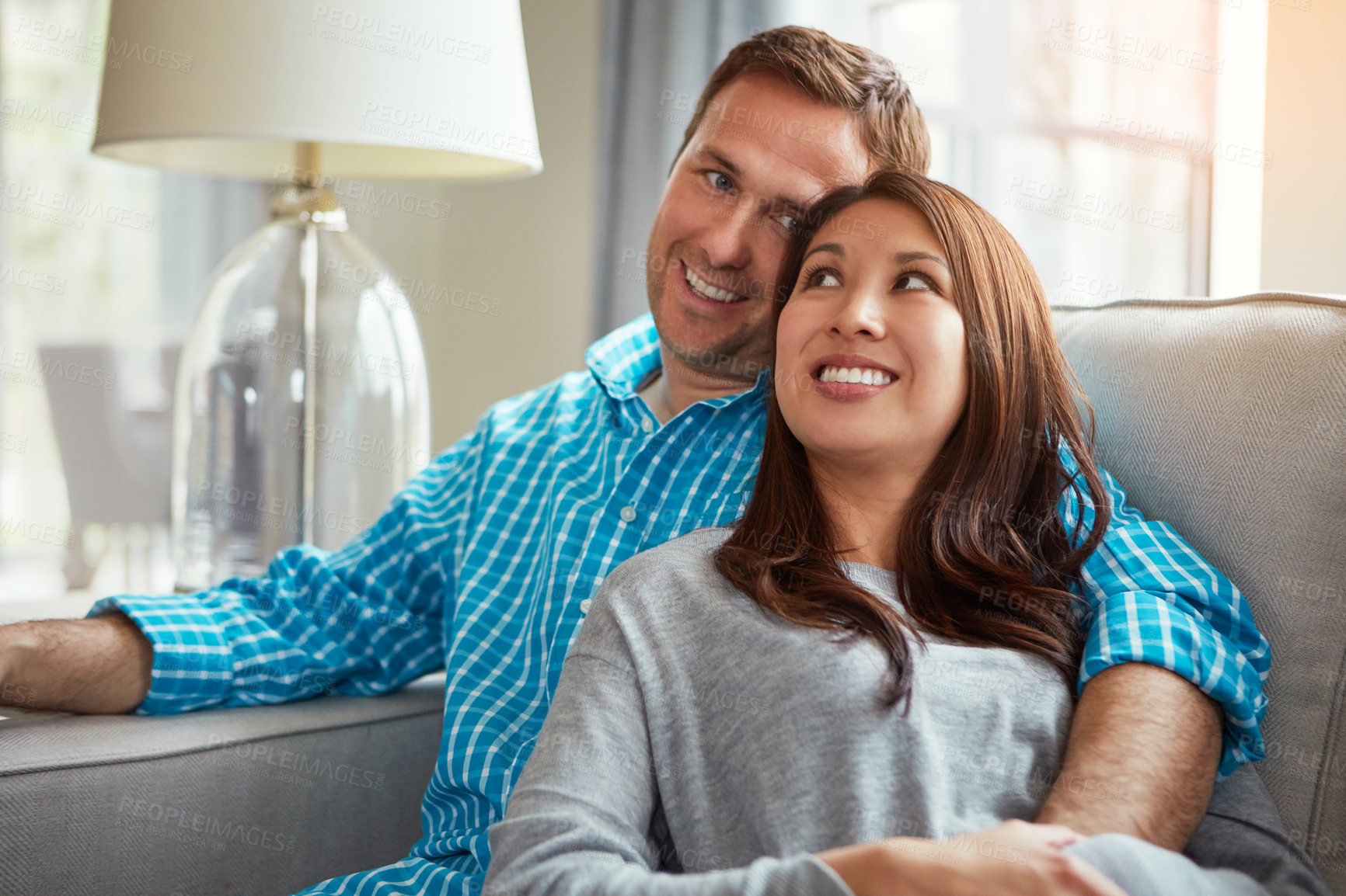 Buy stock photo Shot of a happy young couple relaxing together on the sofa at home