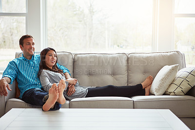 Buy stock photo Shot of a happy young couple relaxing together on the sofa at home