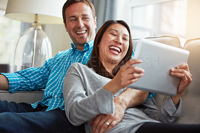 Buy stock photo Laughing, tablet and couple on sofa for social media, scroll internet or relax in living room. Interracial, online and happy woman with man for entertainment, meme or watching comedy movie in home