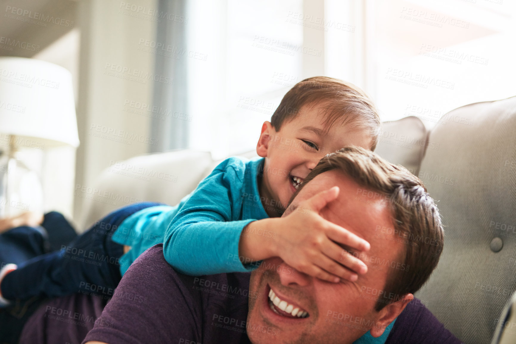 Buy stock photo Laugh, playing and father with child on sofa for bonding, funny and relax together on weekend. Family, home and happy dad with boy cover eyes for fun relationship, love and peekaboo in living room