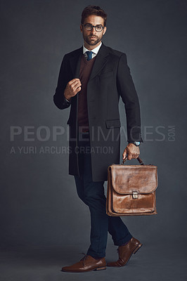Buy stock photo Studio shot of a stylishly dressed young man carrying a bag against a gray background