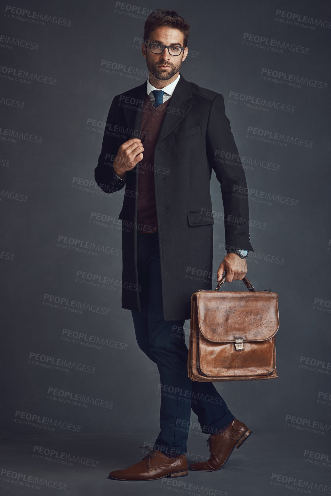 Buy stock photo Studio shot of a stylishly dressed young man carrying a bag against a gray background
