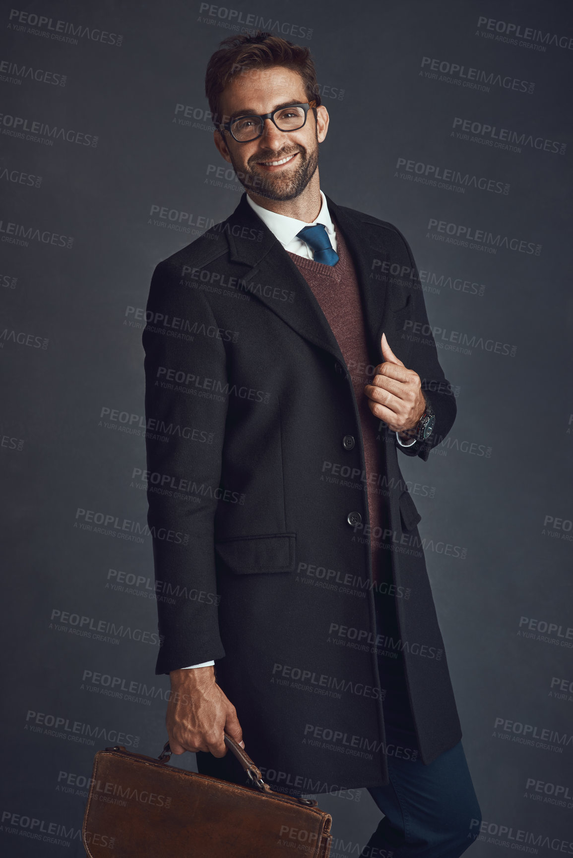 Buy stock photo Studio portrait of a stylishly dressed young man carrying a bag against a gray background