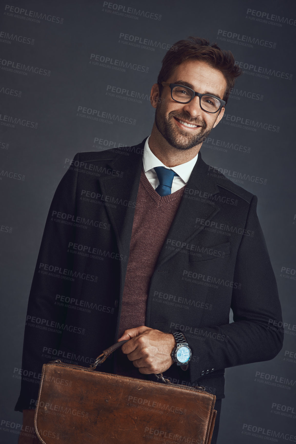 Buy stock photo Studio portrait of a stylishly dressed young man carrying a bag against a gray background