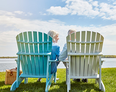 Buy stock photo Shot of an affectionate senior couple relaxing on chairs together outside