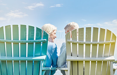 Buy stock photo Shot of an affectionate senior couple relaxing on chairs together outside