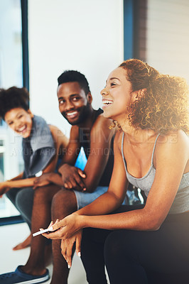 Buy stock photo Shot of three young fit friends having a chat while seated before a workout session inside of a studio