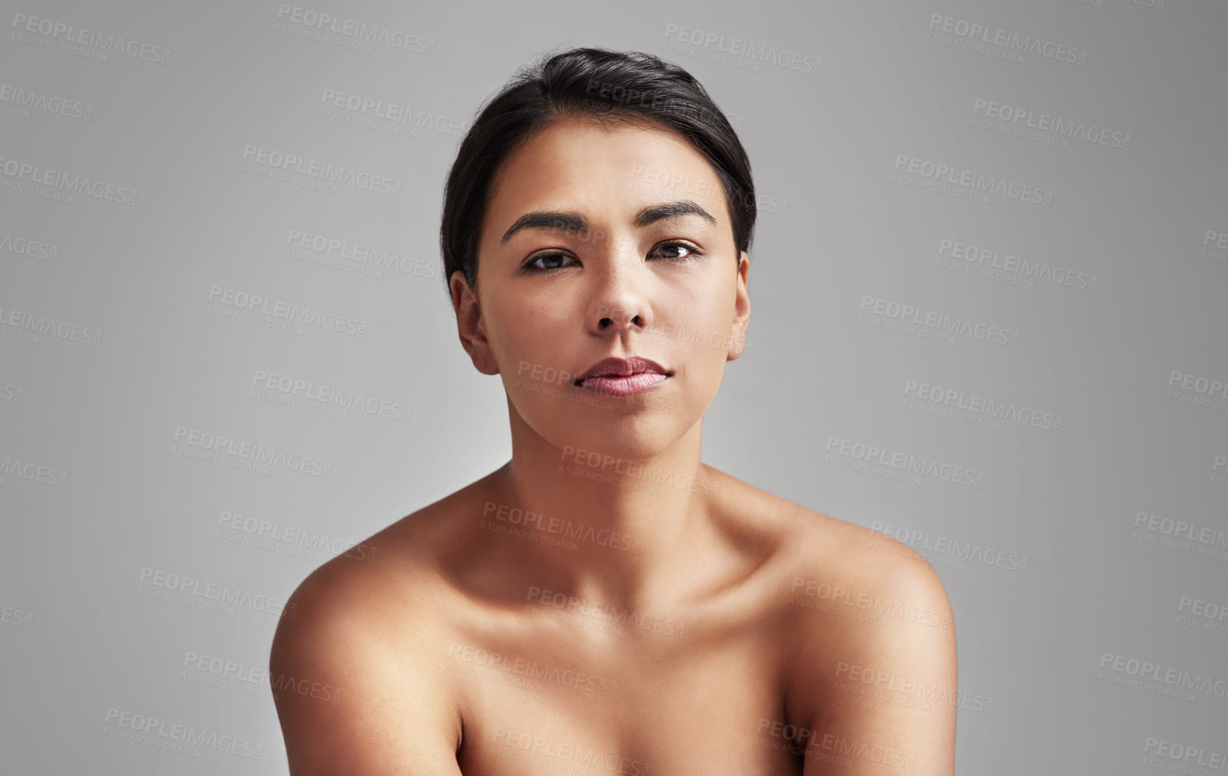 Buy stock photo Studio shot of a young woman with wet hair posing against a gray background