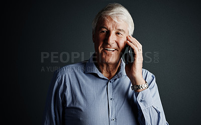Buy stock photo Studio shot of a handsome mature man looking thoughtful while using his cellphone against a dark background