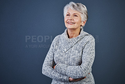 Buy stock photo Studio shot of a cheerful elderly woman standing with her arms folded while looking in the distance