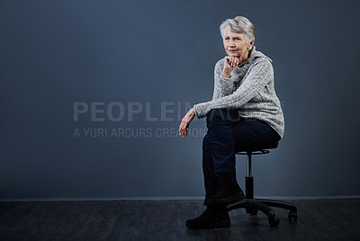 Buy stock photo Studio shot of a confident elderly woman sitting with her her fist under her chin while looking into the distance