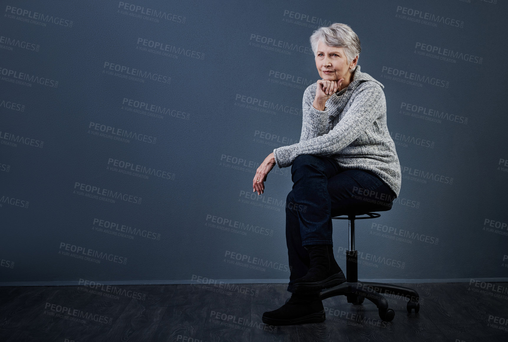 Buy stock photo Studio shot of a confident elderly woman sitting with her her fist under her chin while looking into the distance