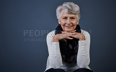 Buy stock photo Studio shot of cheerful elderly woman sitting with her hands under her chin while looking at the camera