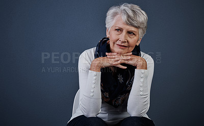 Buy stock photo Studio shot of cheerful elderly woman sitting with her hands under her chin while looking into the distance