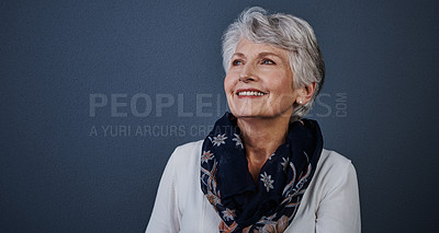 Buy stock photo Studio shot of cheerful elderly woman sitting down and looking into the distance while smiling