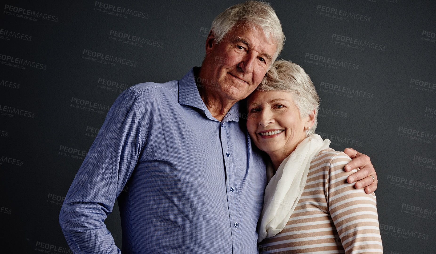 Buy stock photo Studio portrait of an affectionate senior couple posing against a grey background