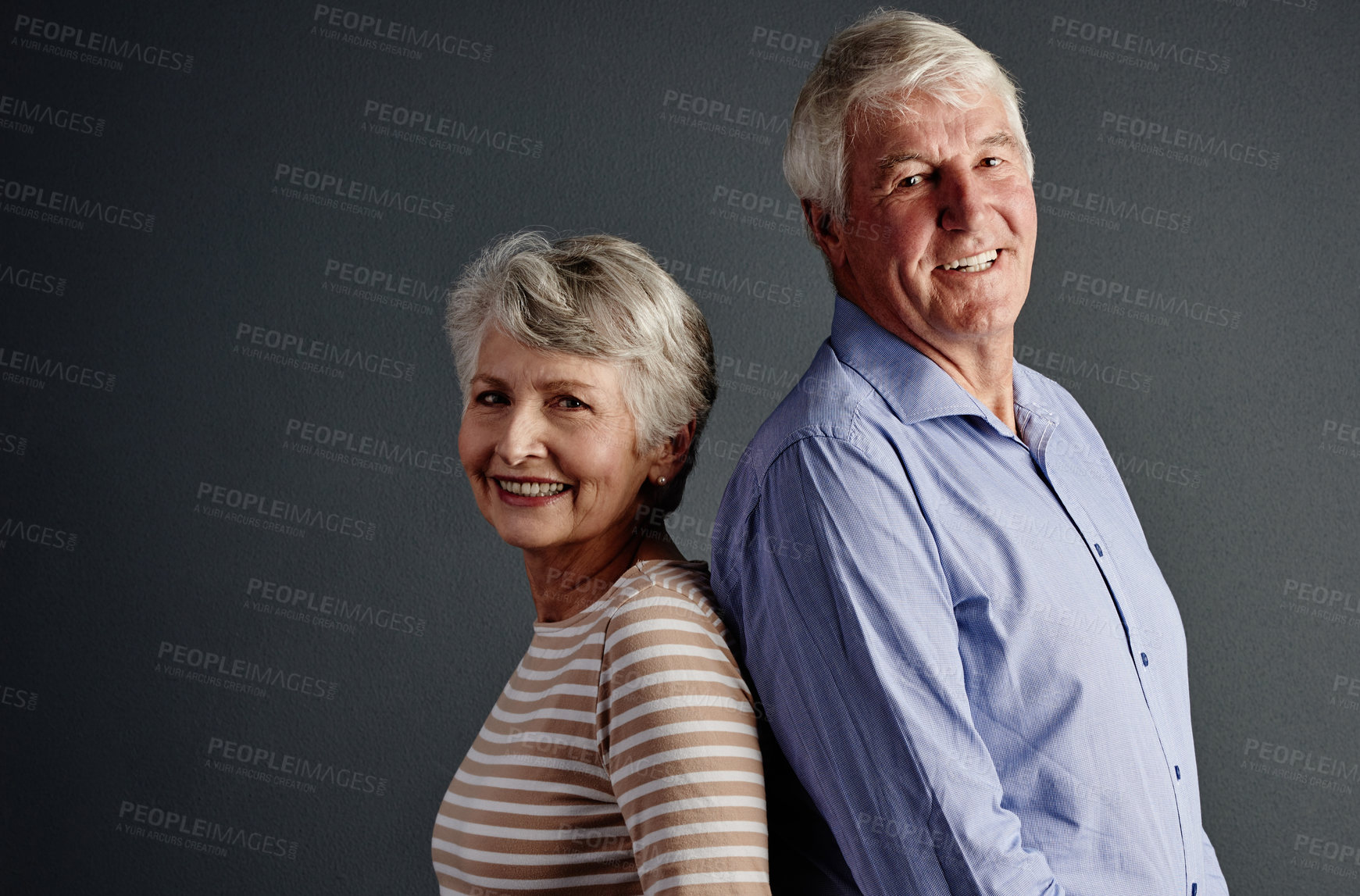 Buy stock photo Studio portrait of an affectionate senior couple posing against a grey background