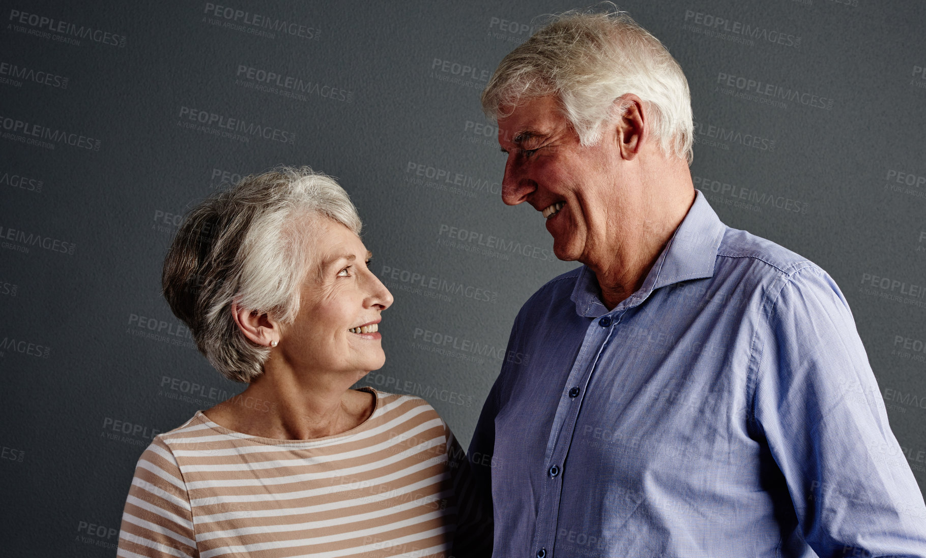 Buy stock photo Studio shot of an affectionate senior couple posing against a grey background