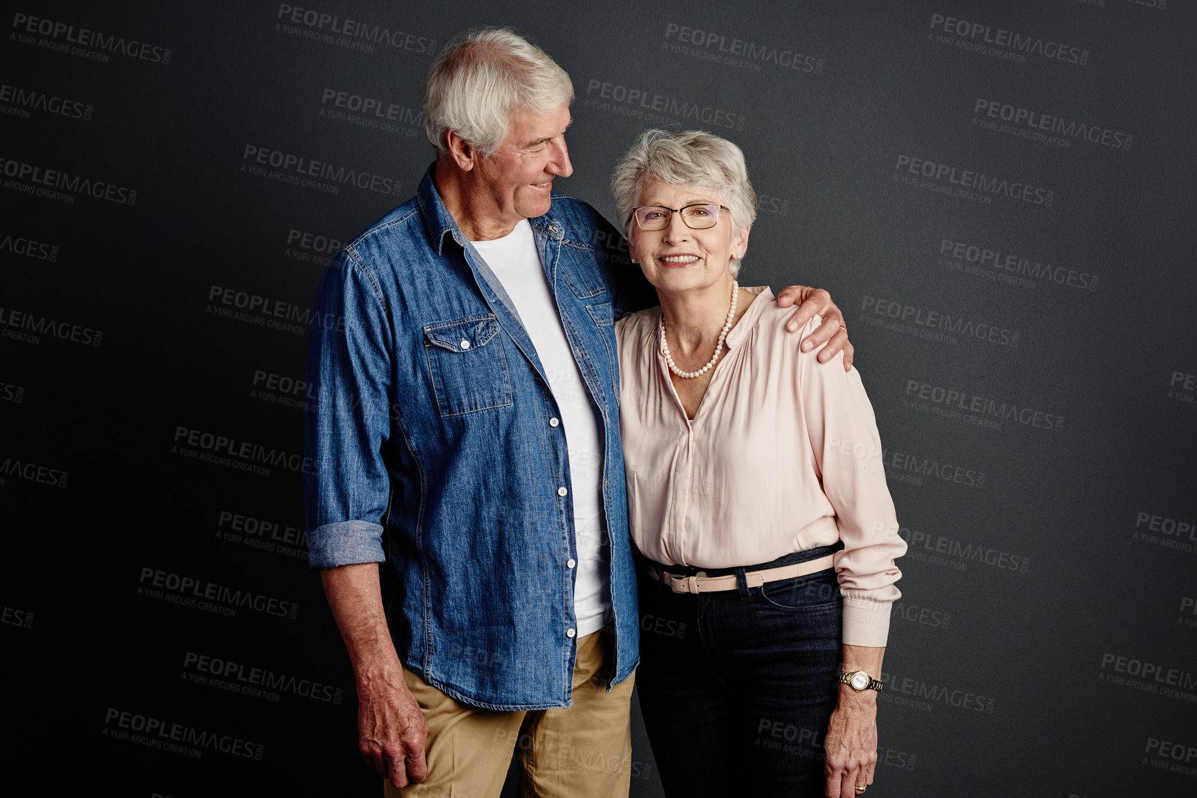 Buy stock photo Studio portrait of an affectionate senior couple posing against a grey background