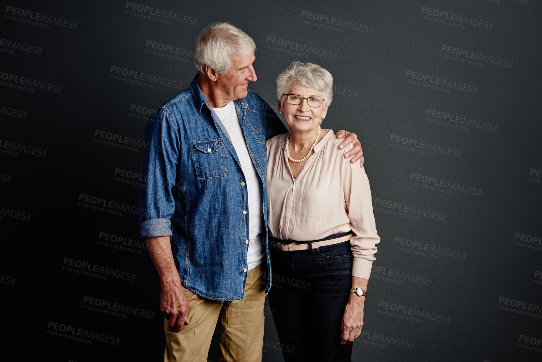 Buy stock photo Studio portrait of an affectionate senior couple posing against a grey background