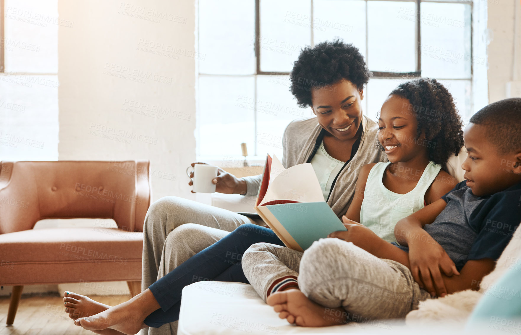 Buy stock photo Shot of a little brother and sister reading a book while their mother watches at home