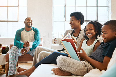 Buy stock photo Black family, reading book and children on sofa, happy and learning for language in home living room. African parents, kids and storytelling for connection, laughing and relax in pajamas in morning