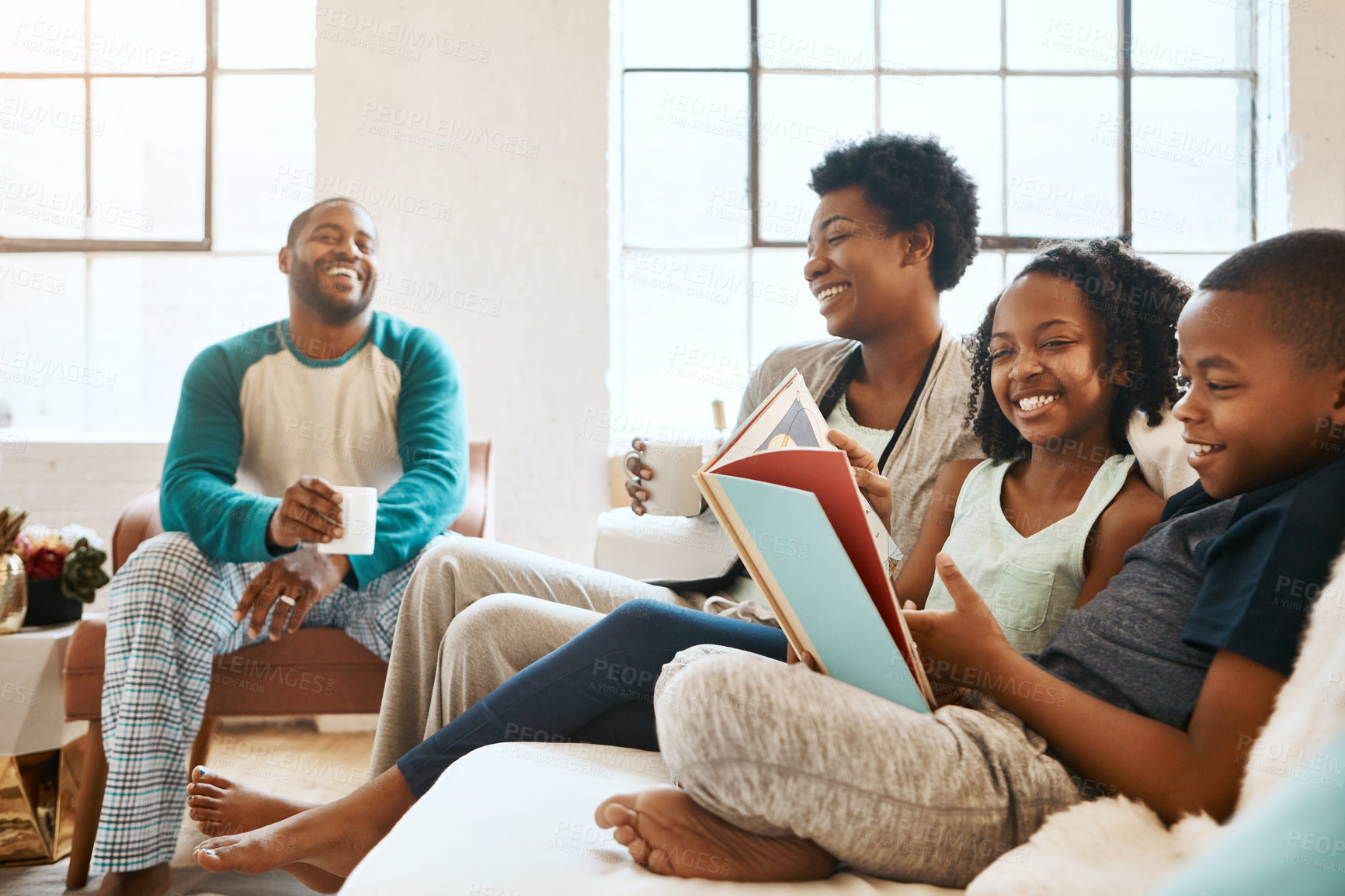 Buy stock photo Black family, reading book and children on sofa, happy and learning for language in home living room. African parents, kids and storytelling for connection, laughing and relax in pajamas in morning