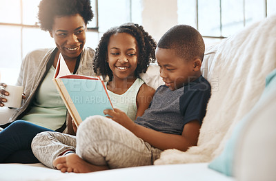 Buy stock photo Shot of a little brother and sister reading a book while their mother watch at home