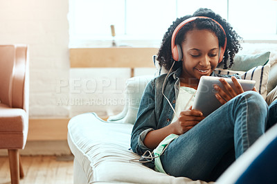 Buy stock photo Digital tablet, headphones and black woman on the sofa to relax while listening to music, radio or podcast. Rest, technology and African lady watch a video on mobile device in her living room at home