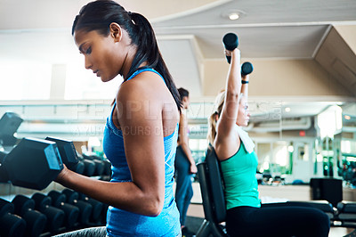 Buy stock photo Cropped shot of attractive young women working out with dumbbells at the gym