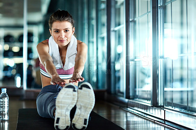 Buy stock photo Shot of an attractive young woman going through her warmup routine in the gym