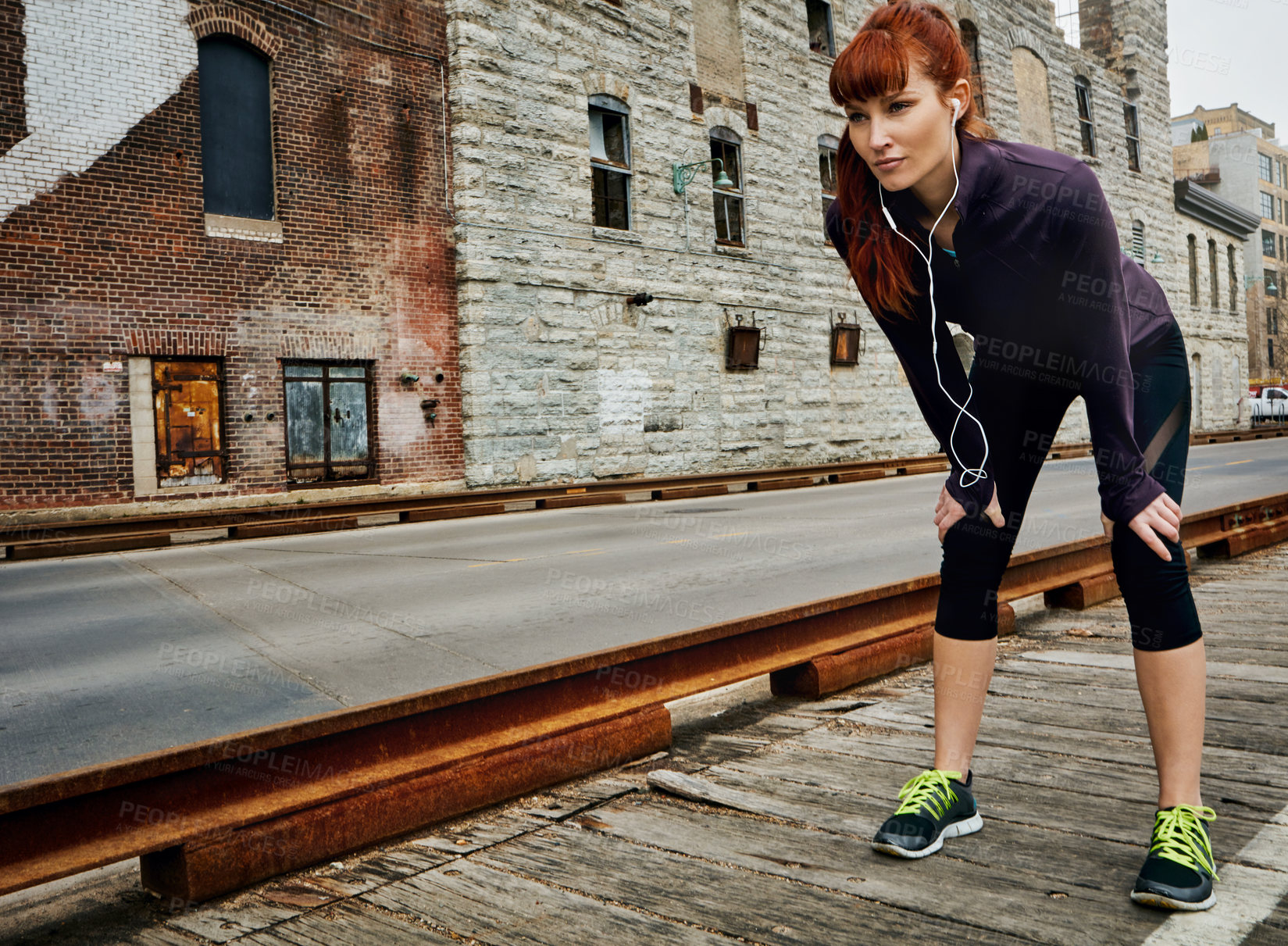 Buy stock photo Shot of a sporty young woman taking a break while running in the city