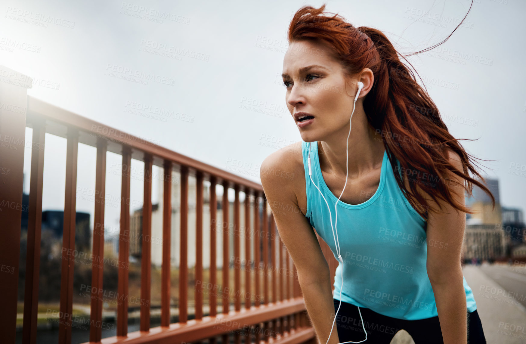 Buy stock photo Shot of a sporty young woman taking a break while running in the city