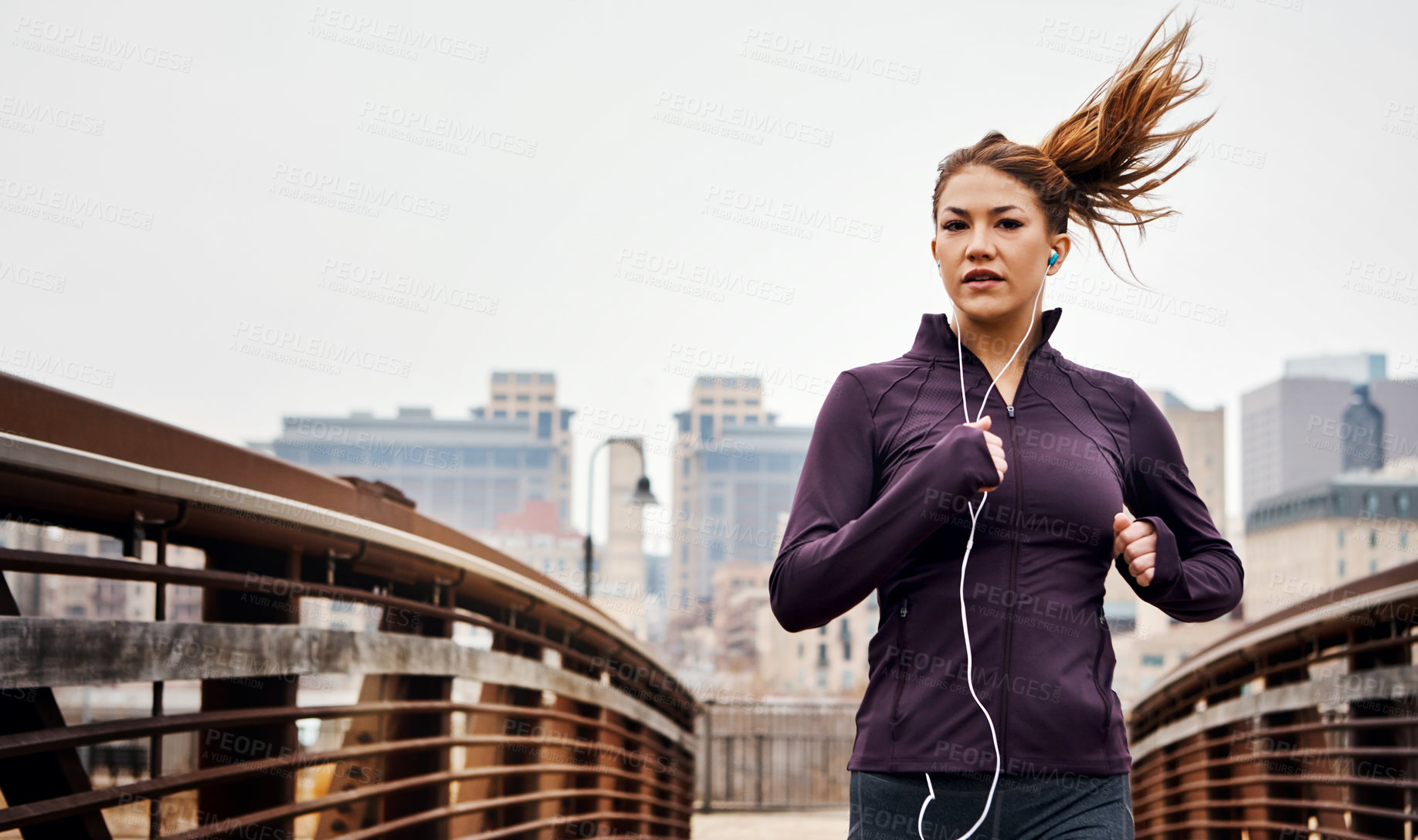 Buy stock photo Cropped shot of an attractive young woman listening to music while running through the city