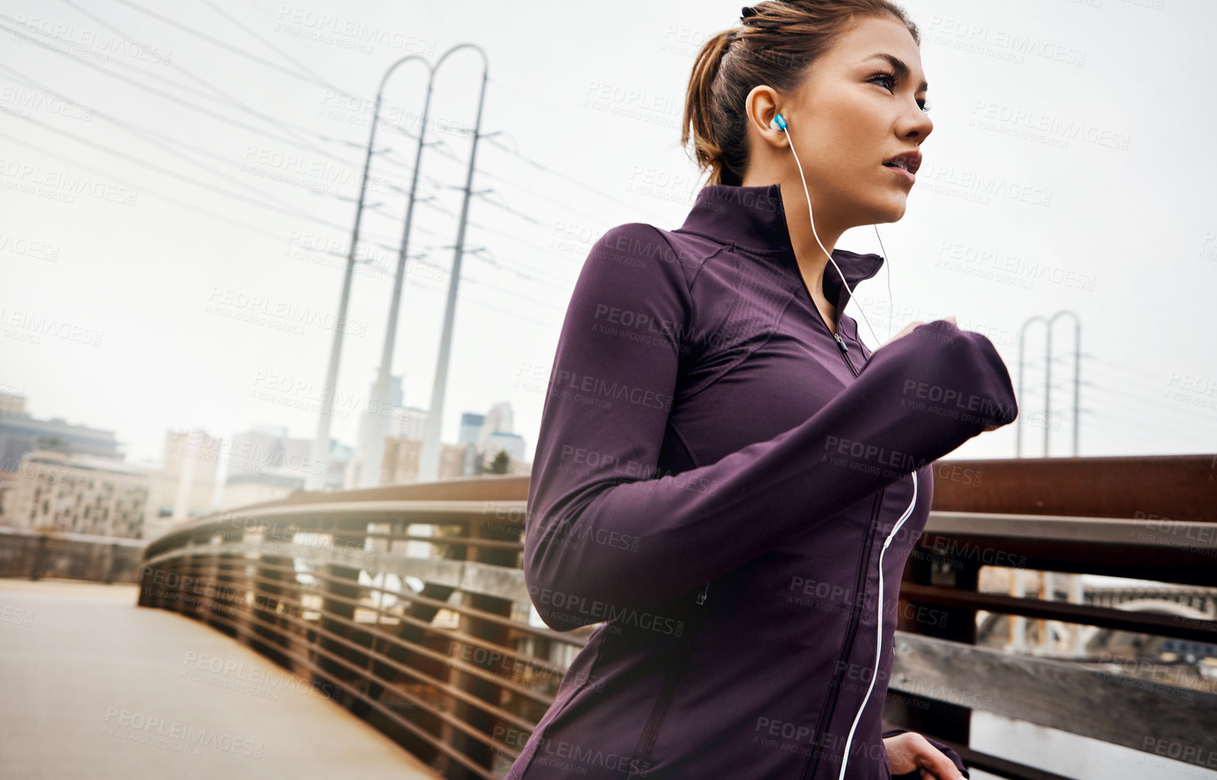 Buy stock photo Cropped shot of an attractive young woman listening to music while running through the city