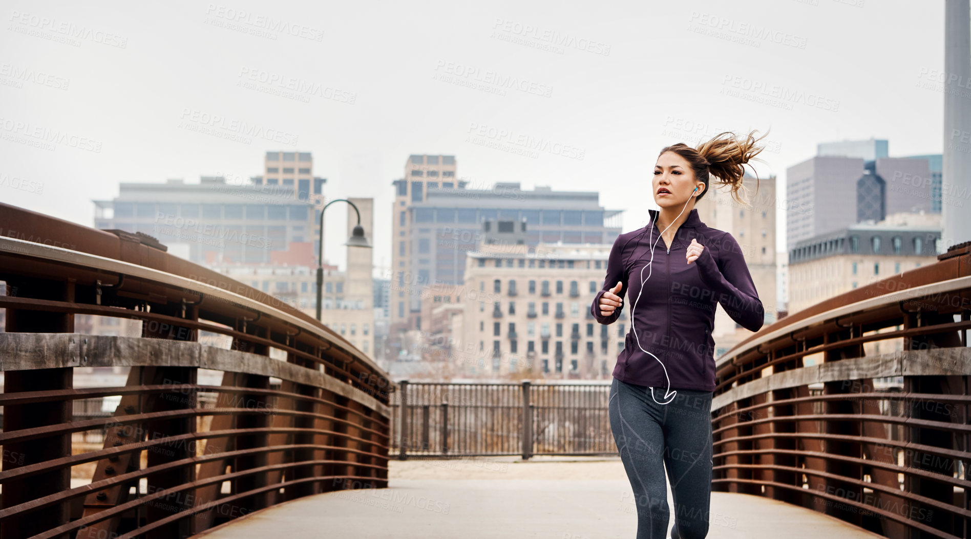 Buy stock photo Cropped shot of an attractive young woman listening to music while running through the city