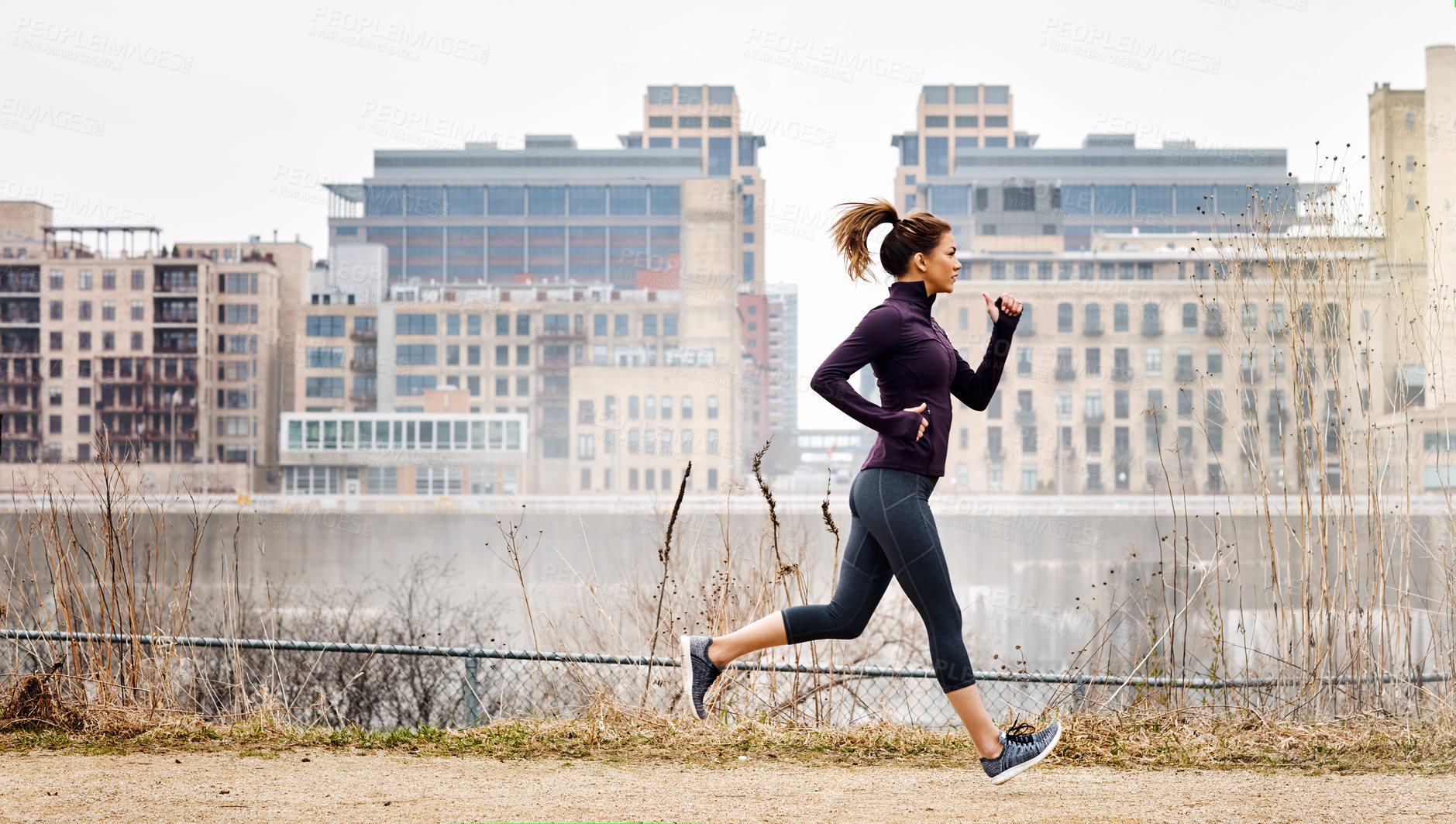 Buy stock photo Full length shot of an attractive young woman taking a run through the city